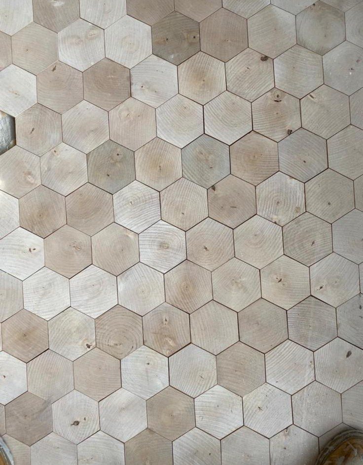 Close-up of bespoke hexagonal end-grain timber flooring with visible growth rings, natural grain variations and precisely fitted wooden blocks.
