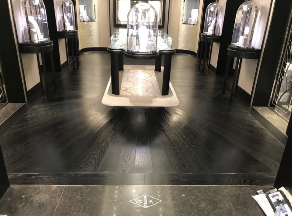 Dark timber flooring in a display interior with glass cabinets and a polished stone threshold.